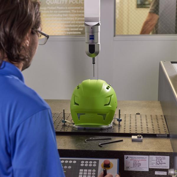 Worker operates machinery that makes a helmet